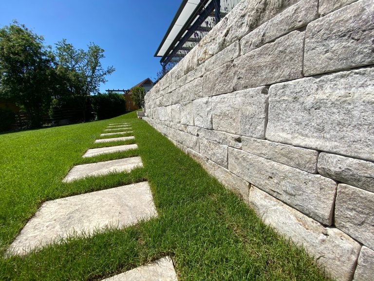 Steinmauer, Steinplatten und Rasenfläche